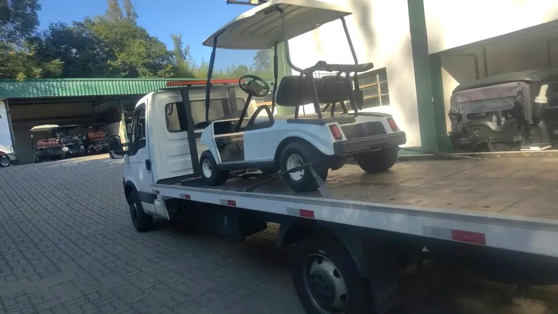 Carrinho de golfe sobre caminhão plataforma