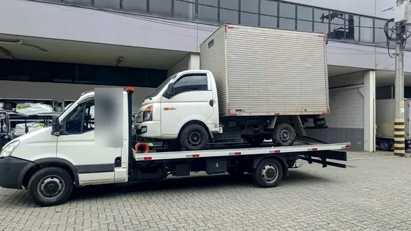 Pequeno caminhão baú branco sendo transportado