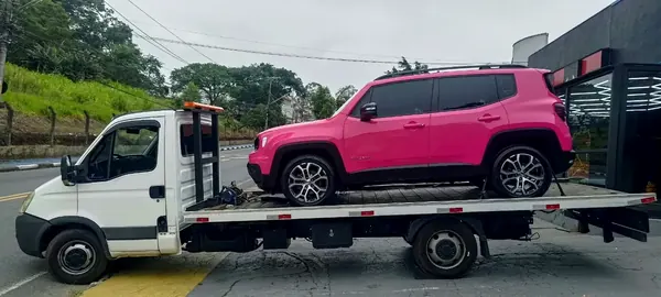 SUV rosa em caminhão plataforma branco
