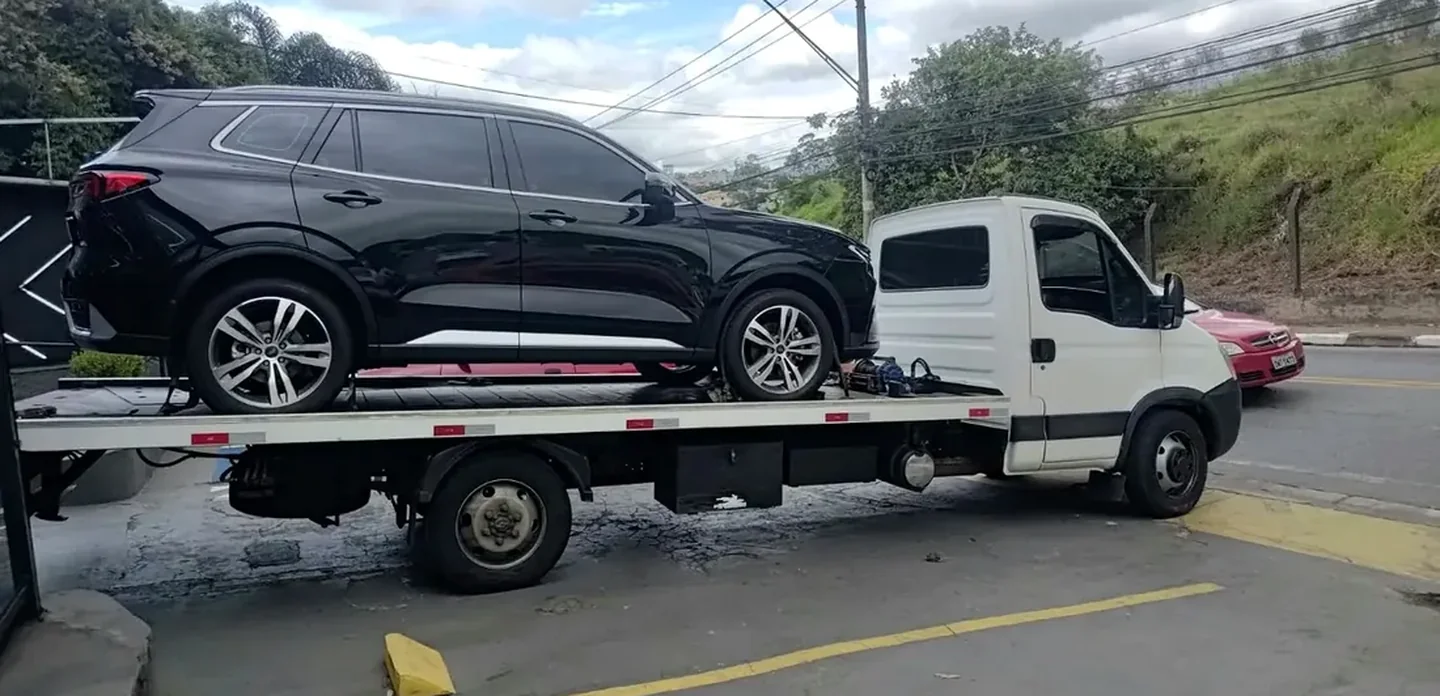 SUV preto sendo transportado em caminhão plataforma branco